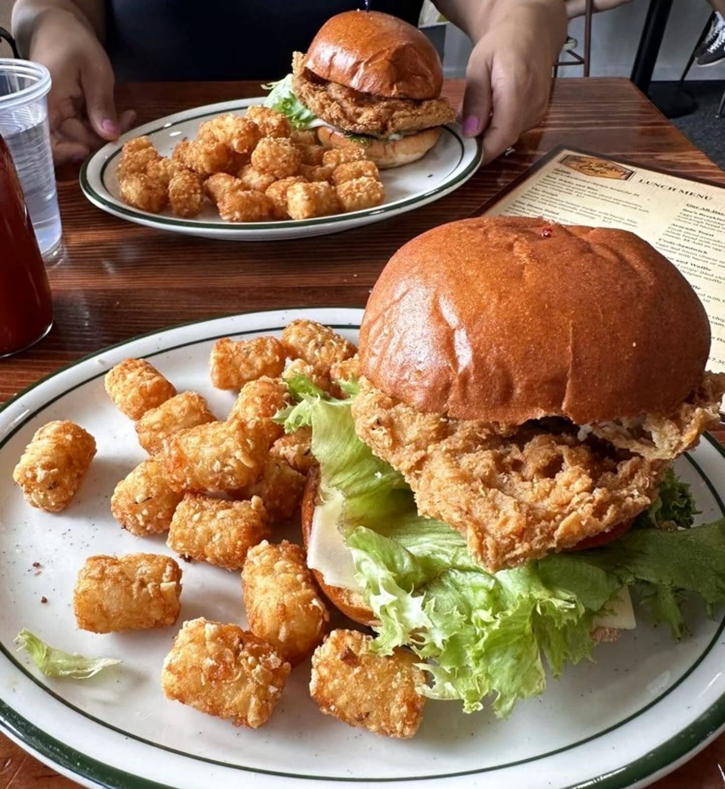 Crispy fried chicken sandwich with lettuce and cheese, served with tater tots