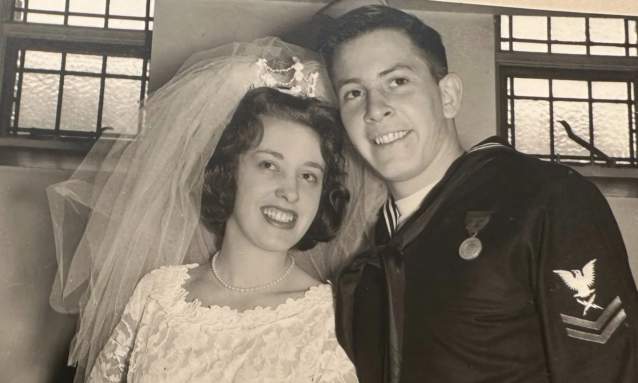 Vintage black-and-white wedding photograph of a bride and a groom in a Navy uniform.
