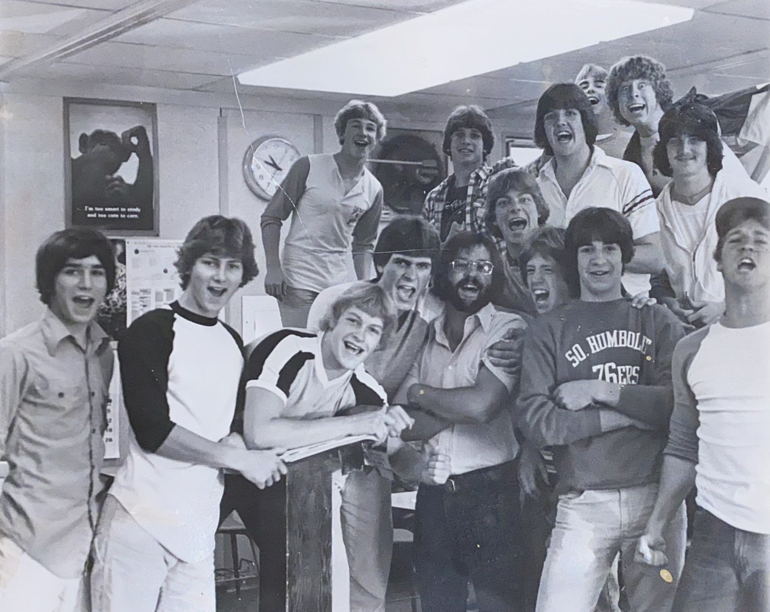A large group of smiling young men in an office or classroom setting.