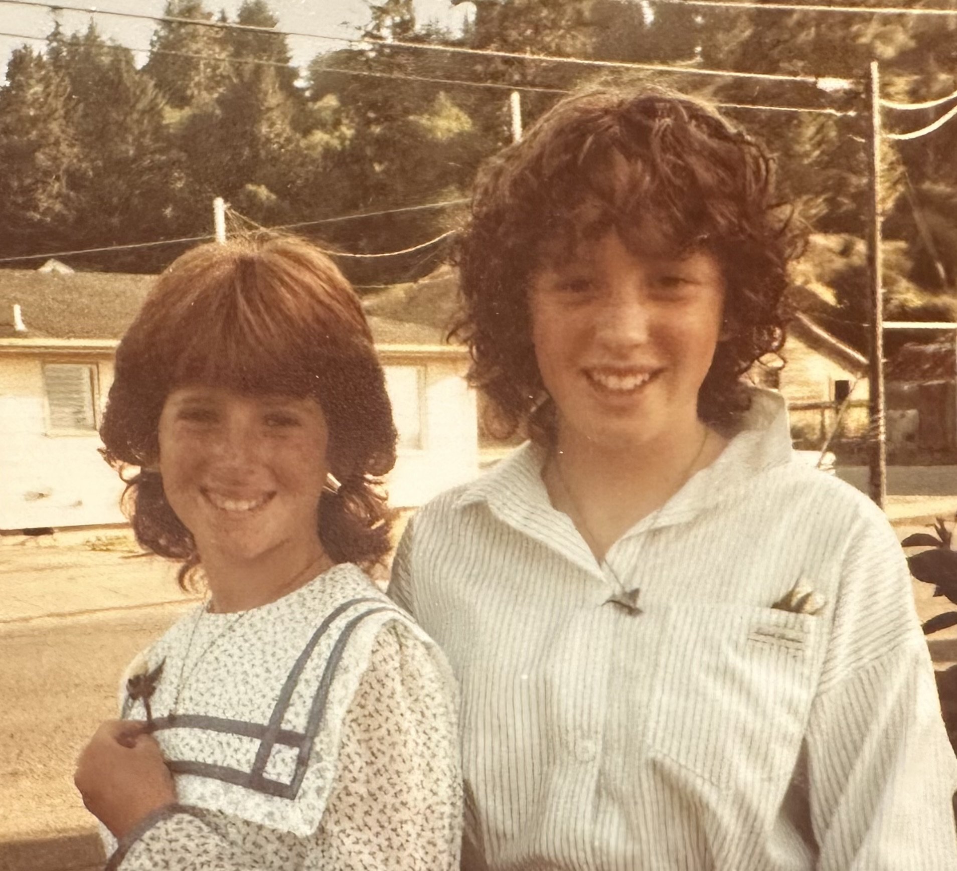 Vintage photo of two smiling girls standing outside.