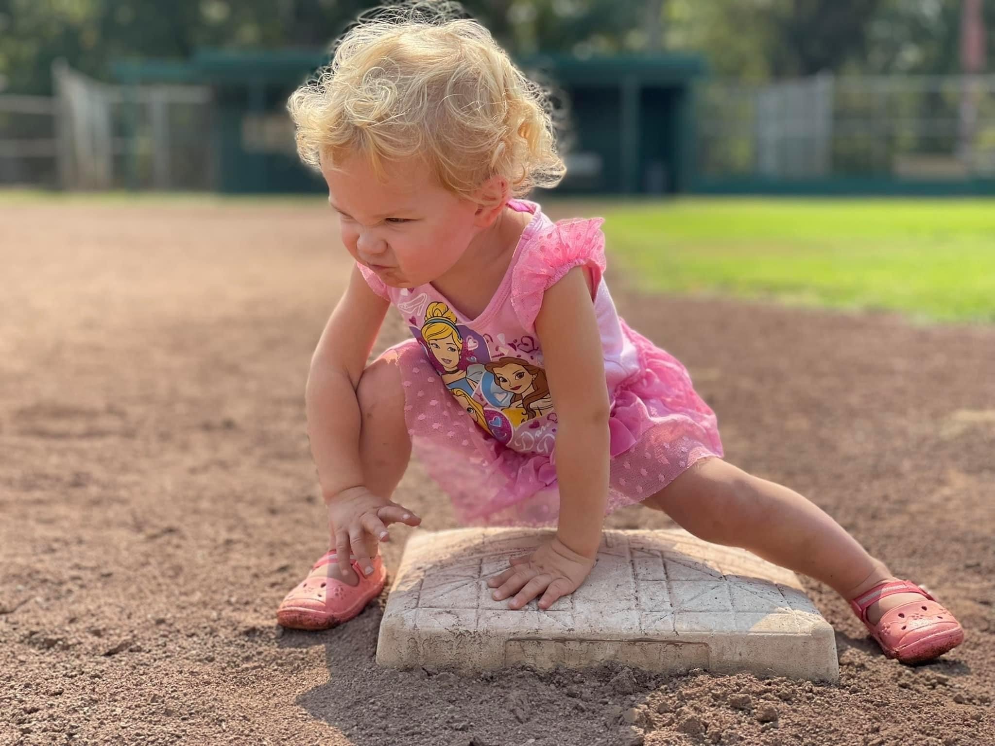 Toddler girl focused on a baseball base