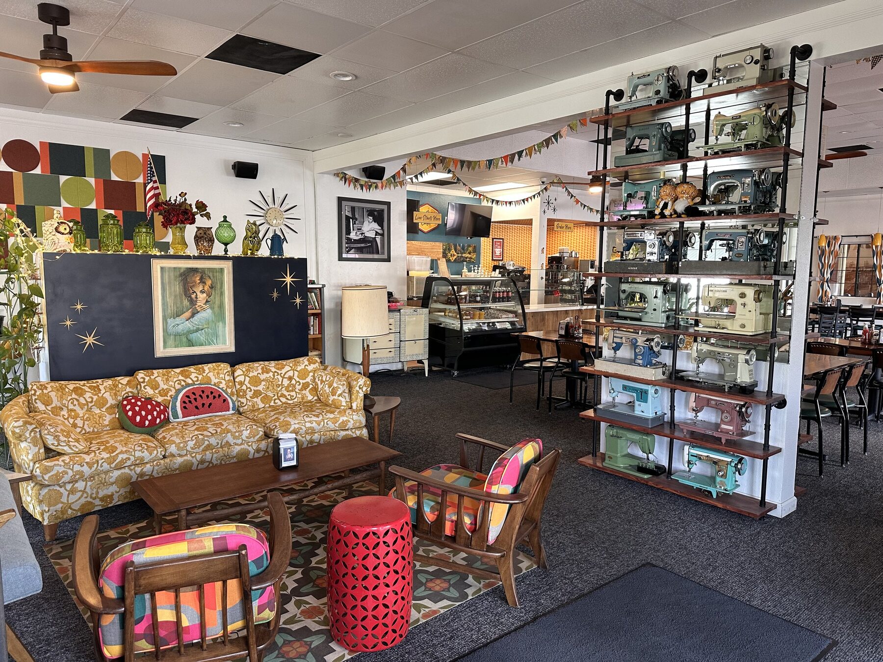 Cozy vintage lounge seating with a shelf of colorful antique sewing machines at Bee's Bakery Cafe